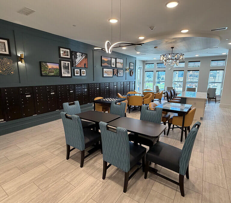 Modern apartment community lounge with dining tables, mailboxes, and seating area