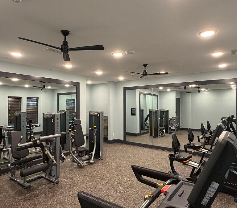 Apartment fitness center with cardio machines, strength equipment, and mirrored walls