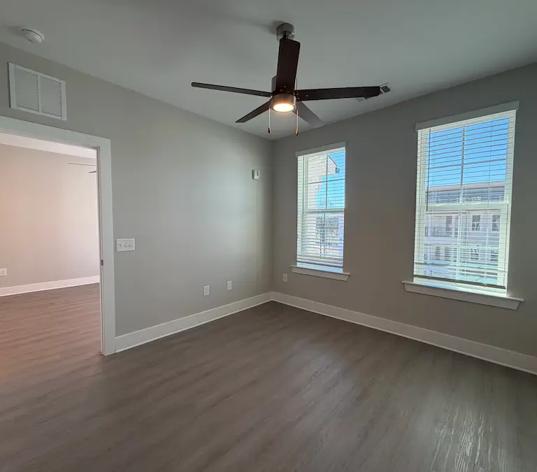 Empty apartment bedroom with wood flooring and double windows