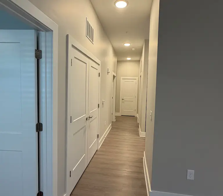 Apartment hallway with wood flooring and multiple room access