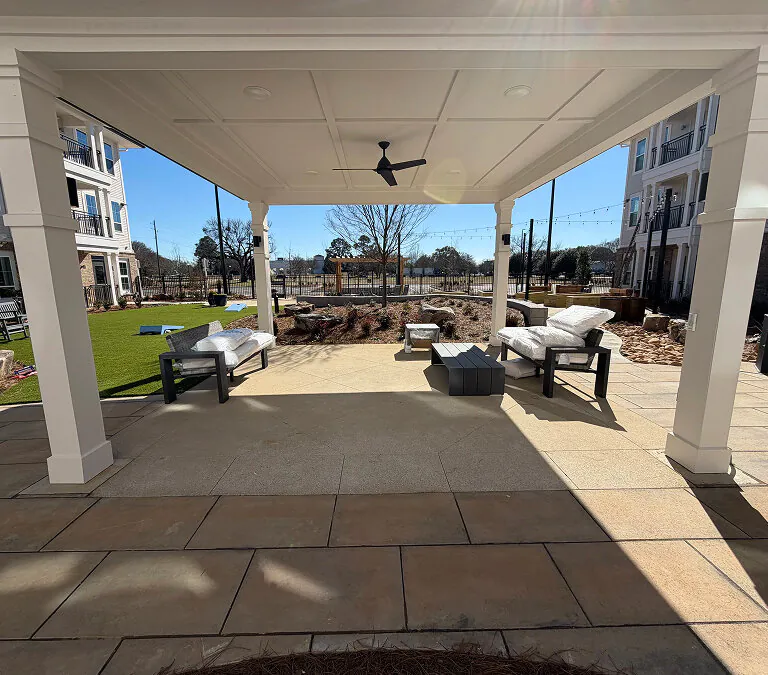 Outdoor covered patio with seating area and landscaped courtyard at apartment community