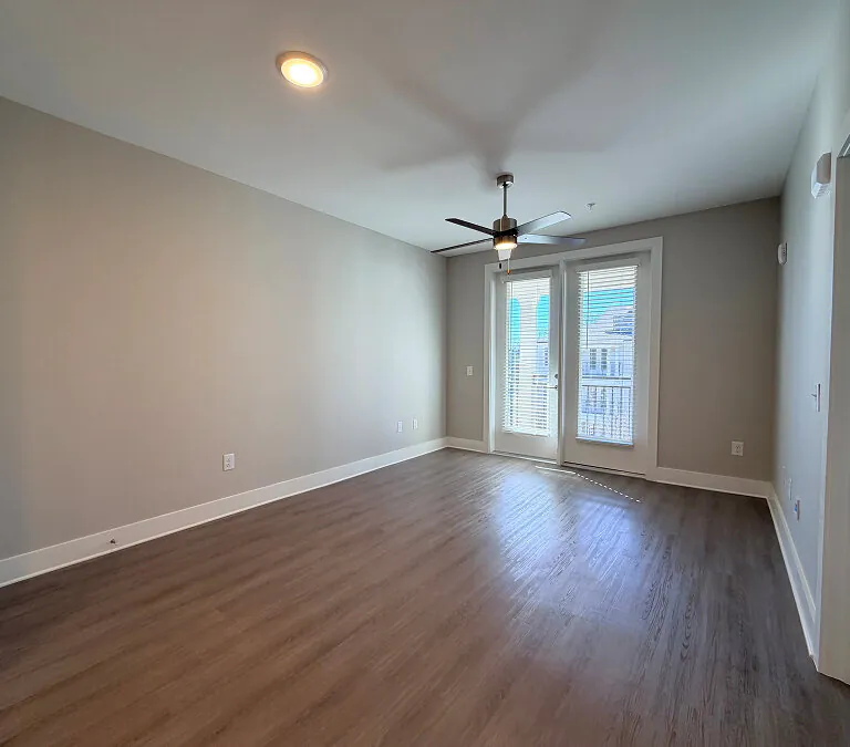 Empty apartment living room with wood flooring and balcony access
